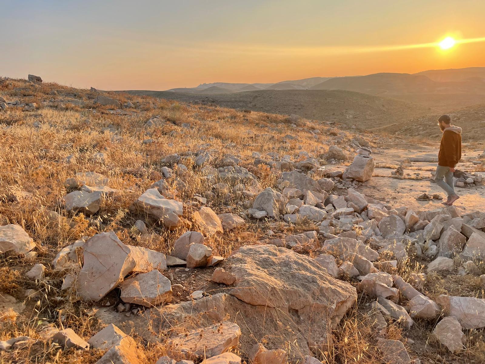 A lone man standing on a mountain ridge at sunrise